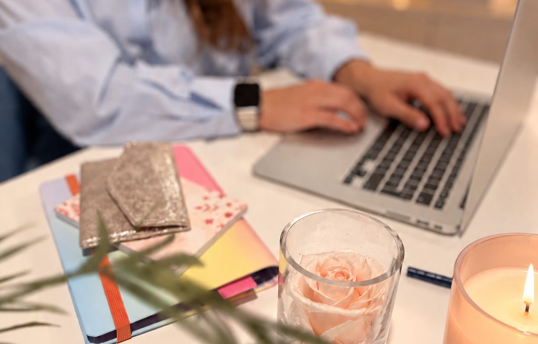 Mains sur le clavier d’un ordinateur, bureau soigné avec une rose